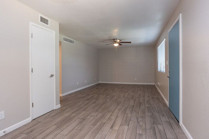 Chic living room with elegant wood-style flooring and sleek ceiling fan, offering a fresh and inviting atmosphere.