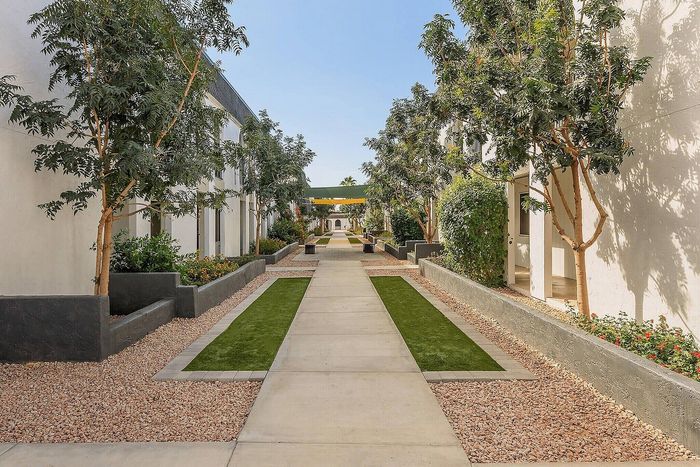 Inviting outdoor corridor lined with lush trees and elegant pathways in a modern apartment complex.