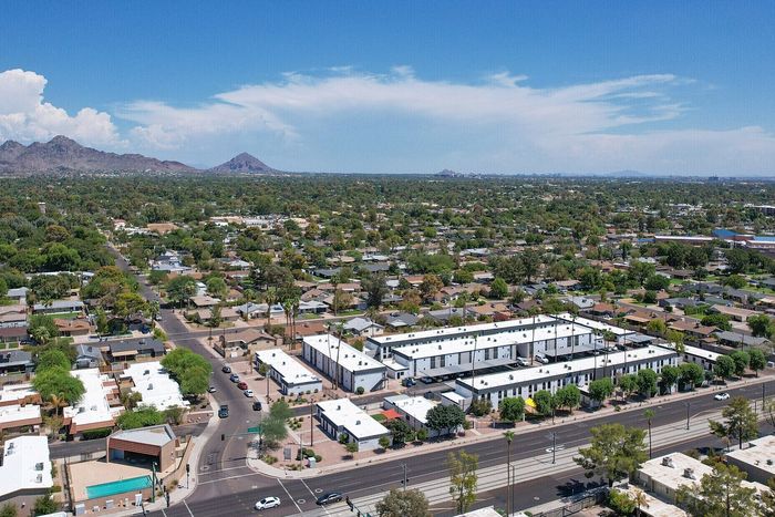 Aerial view of a modern apartment complex surrounded by lush greenery and scenic mountain views, offering a perfect blend of urban living and natural beauty.