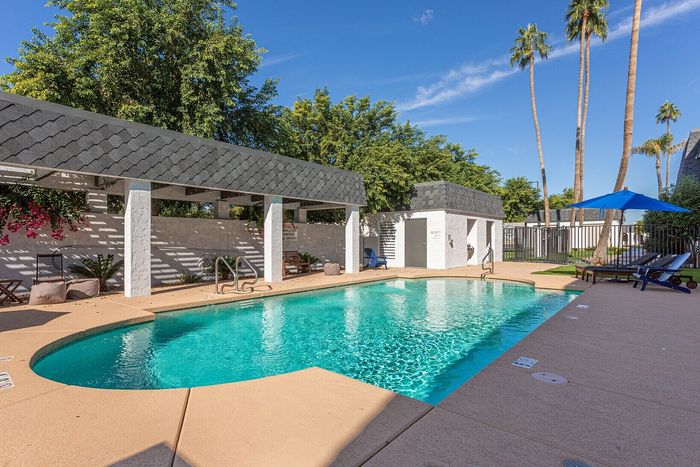 Inviting outdoor pool area with sparkling water, surrounded by lush greenery and comfortable lounge chairs, perfect for relaxation and enjoyment.