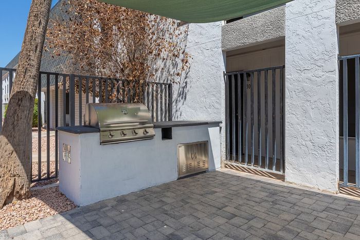 Charming outdoor patio with built-in stainless steel grill and shaded seating, perfect for al fresco dining and entertaining.