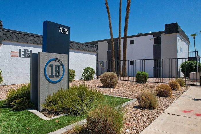 Charming apartment complex entrance with vibrant landscaping and stylish signage displaying 'Station 19' and address number 7625.