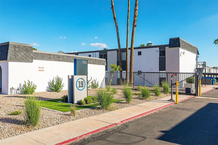 Inviting apartment complex with modern exterior, featuring clean architecture and vibrant landscaping under a clear blue sky.