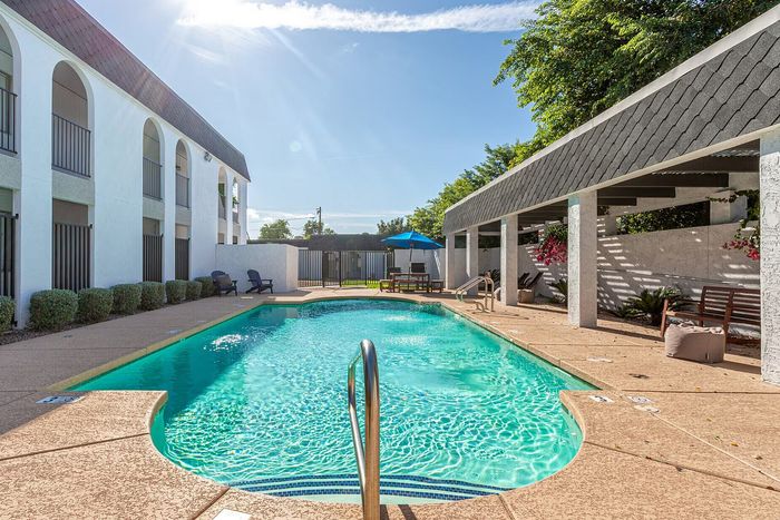 Inviting outdoor pool area with lush greenery and elegant arches, perfect for relaxation and leisure.