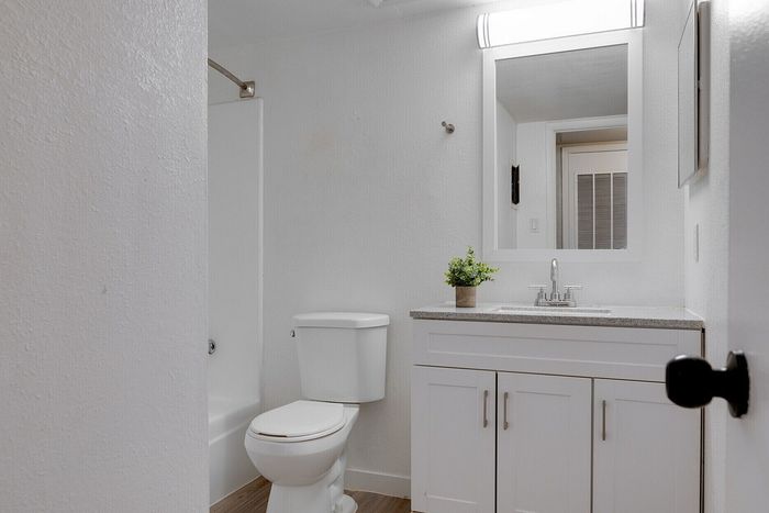 Modern bathroom with sleek white cabinetry, elegant vanity mirror, and sophisticated light fixture.
