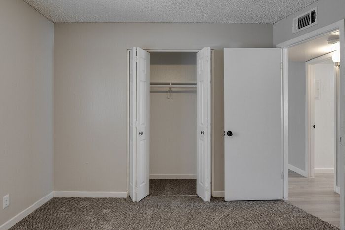 Inviting bedroom with plush carpeting and ample closet space in a modern apartment.