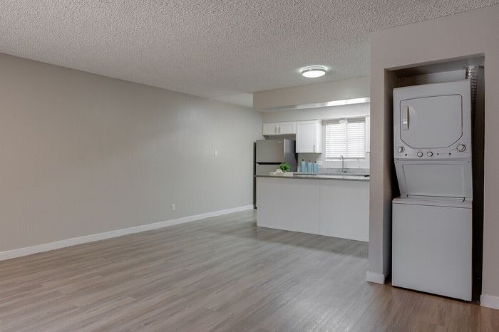 Spacious open-plan apartment with modern kitchen, sleek countertops, and built-in laundry area, offering a blend of style and convenience.