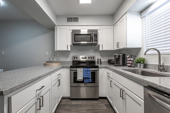 Modern kitchen featuring sleek white cabinetry, stainless steel appliances, and elegant granite countertops with ambient lighting.
