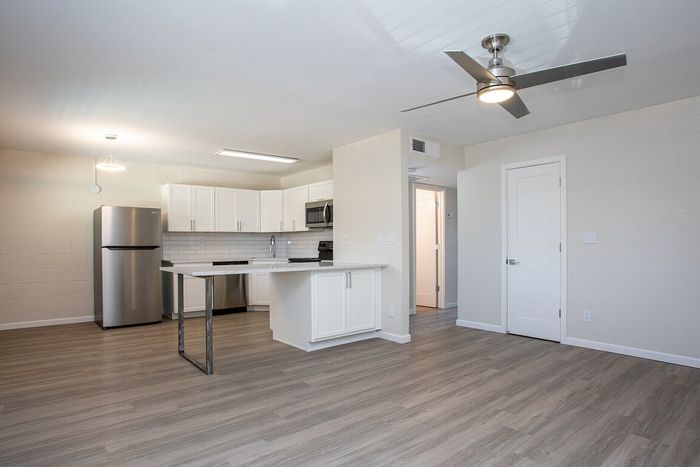Bright open-plan kitchen with modern stainless steel appliances, sleek countertops, and elegant wood-style flooring.