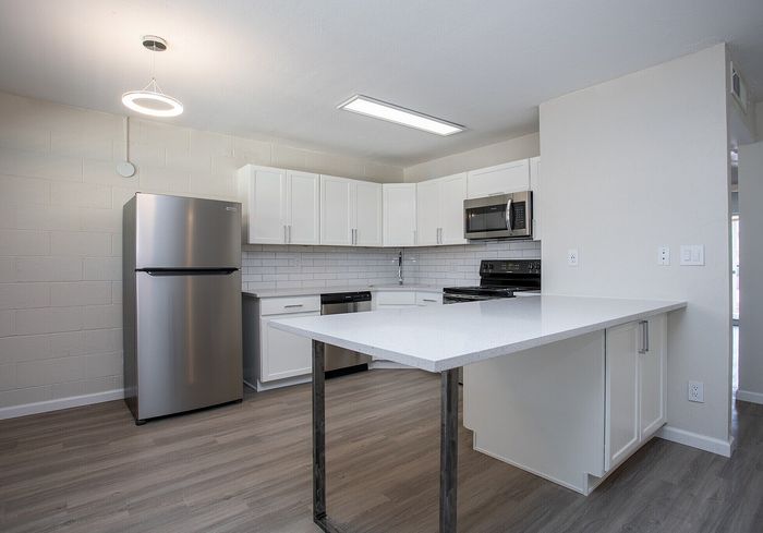 Contemporary kitchen with sleek stainless steel appliances, bright white cabinets, and a modern island.