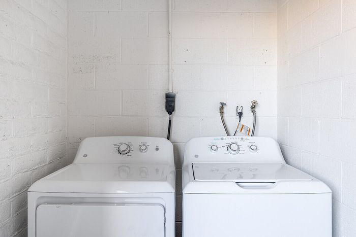 Chic laundry area featuring modern washer and dryer set against a sleek brick wall backdrop.