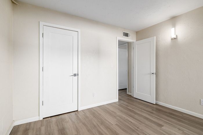 Bright and inviting room with elegant light wood flooring, textured neutral walls, and modern doors offering a sleek and sophisticated touch.
