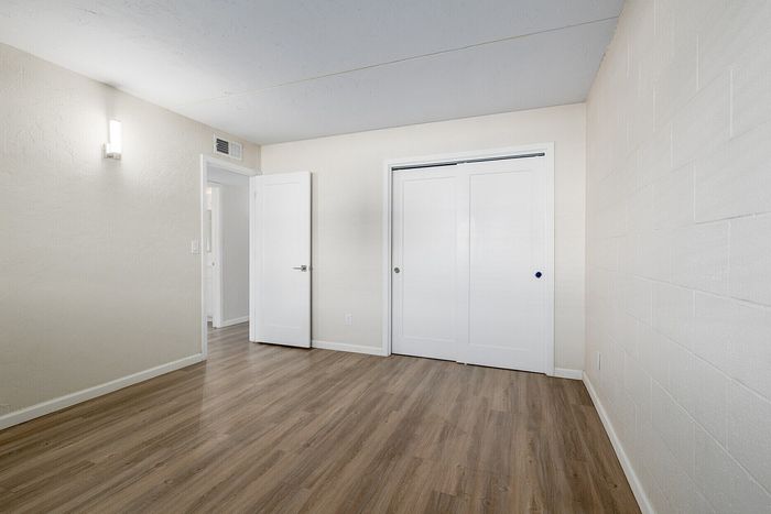 Bright and spacious room with elegant wood flooring and modern closet doors, perfect for personalization in a welcoming home.