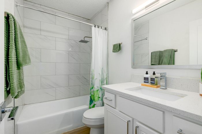 Modern bathroom with sleek white vanity, stylish tiled shower, and vibrant green accents for a refreshing ambiance.