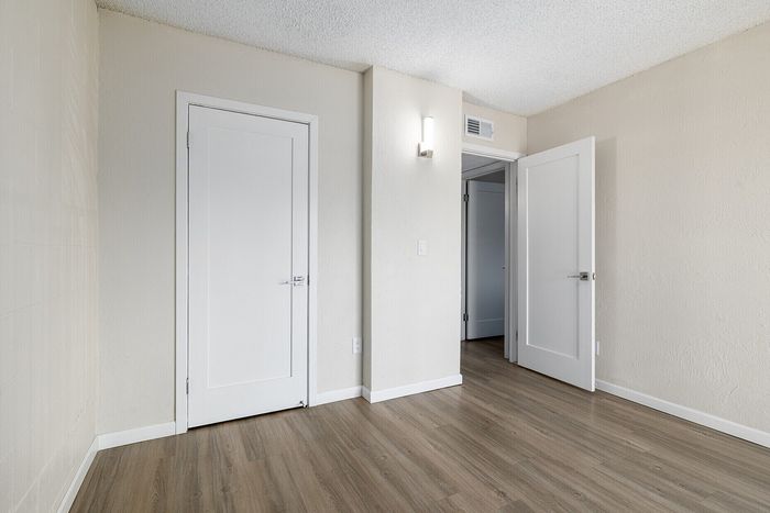 Bright and modern room with elegant wood flooring, crisp white doors, and soft textured walls, offering a blank canvas for personal style.