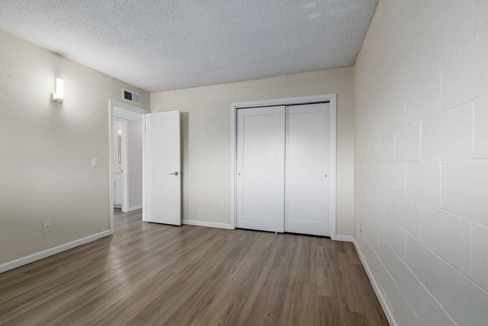 Bright and airy bedroom with modern wood flooring, sleek white closet doors, and recessed lighting creating a warm and inviting atmosphere.