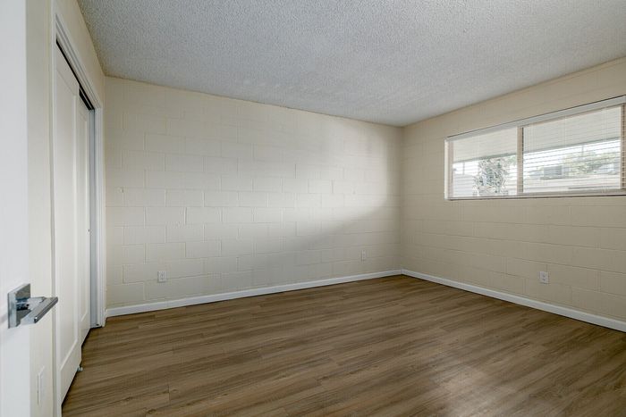 Bright and inviting bedroom with sleek laminate flooring, ample natural light, and a spacious closet.