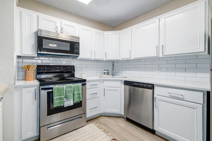 Modern kitchen with sleek stainless steel appliances, elegant white cabinets, and subway tile backsplash.
