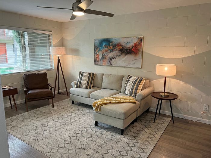 Modern living room with cozy beige sectional, abstract wall art, warm lighting, and stylish accents.