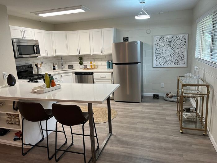 Modern kitchen with sleek white cabinetry, stainless steel appliances, and a stylish breakfast bar, perfect for entertaining.