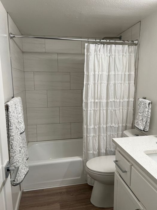 Modern bathroom featuring elegant white subway tile, a chic white shower curtain, and a sleek vanity.