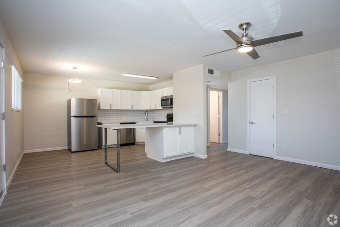 Modern open-concept apartment kitchen with stainless steel appliances, elegant wooden flooring, and ample natural light.