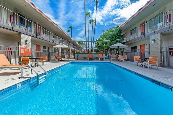 Charming apartment complex featuring a sparkling outdoor pool surrounded by comfortable seating and vibrant landscaping.