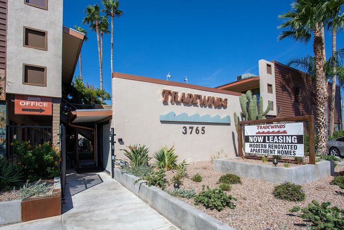 Inviting facade of Tradewinds Apartments with lush landscaping and modern design, now leasing renovated apartment homes.
