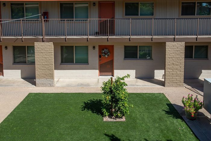 Charming two-story apartment exterior with manicured lawn, vibrant greenery, and inviting entrances offering a welcoming atmosphere.