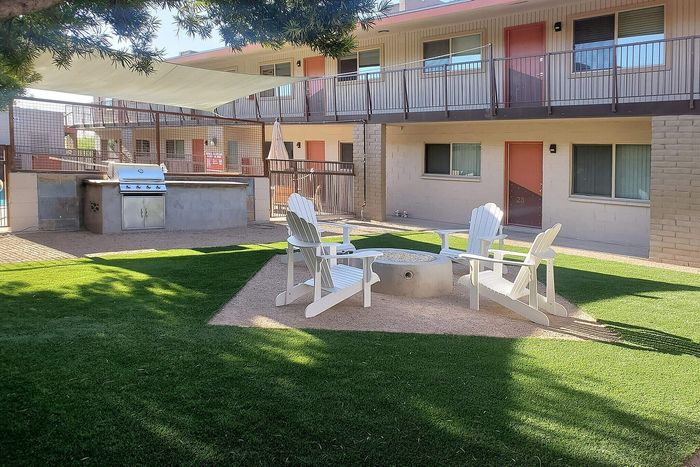 Inviting outdoor area with modern grill, cozy fire pit surrounded by Adirondack chairs, perfect for entertaining.