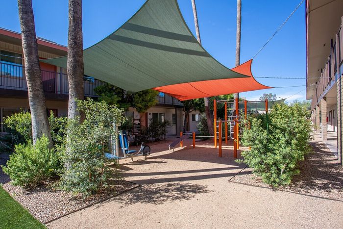Inviting outdoor courtyard with modern shade sails and a playful children's area surrounded by lush greenery.