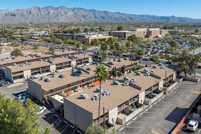 Charming apartment complex surrounded by scenic mountain views, featuring ample parking and lush palm trees.