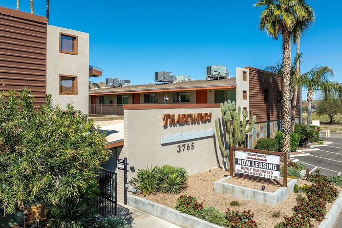 Inviting Tradewinds apartment complex with lush landscaping, showcasing modern design and newly renovated units.