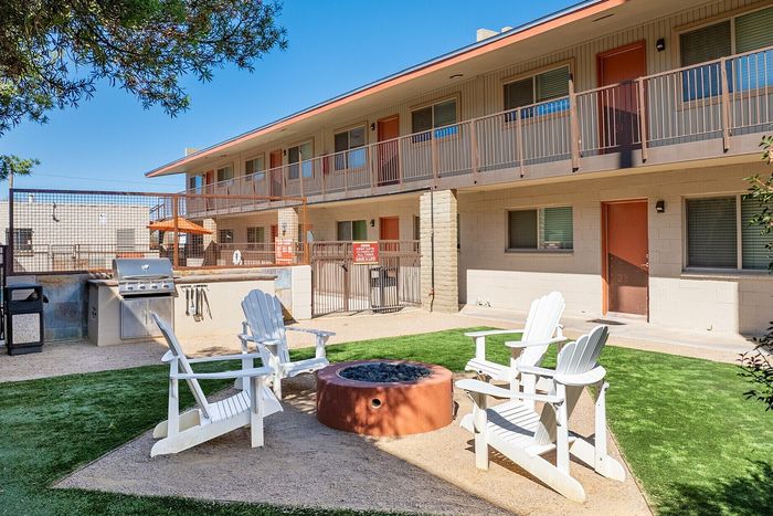 Inviting apartment courtyard with comfortable seating around a cozy fire pit, complete with a BBQ grill for outdoor gatherings.