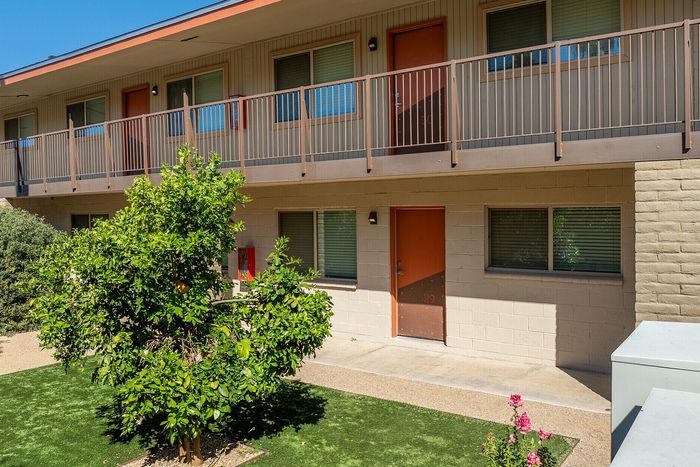 Charming apartment exterior with a modern balcony, vibrant greenery, and a lush garden, offering a serene living environment.
