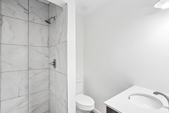 Chic bathroom with elegant marble-tiled shower, modern fixtures, and sleek vanity.
