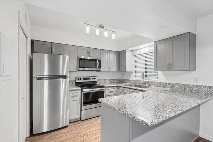 Modern kitchen with sleek stainless steel appliances, elegant granite countertops, and stylish gray cabinetry, offering a sophisticated and inviting space for culinary creations.