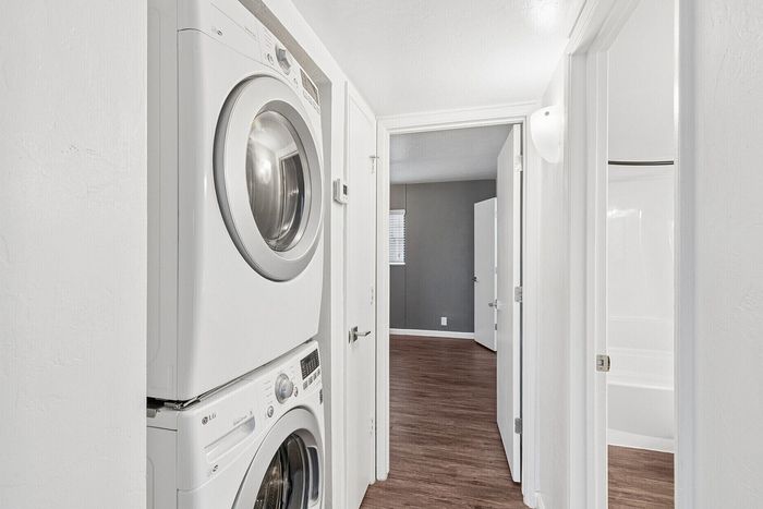 Modern apartment interior featuring gleaming hardwood floors, convenient in-unit stacked washer and dryer, and inviting hallway leading to spacious rooms.