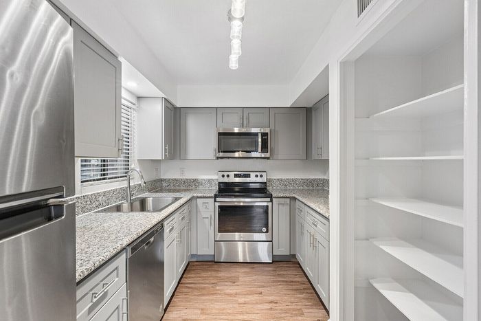 Modern kitchen with sleek stainless steel appliances, granite countertops, and ample open shelving.