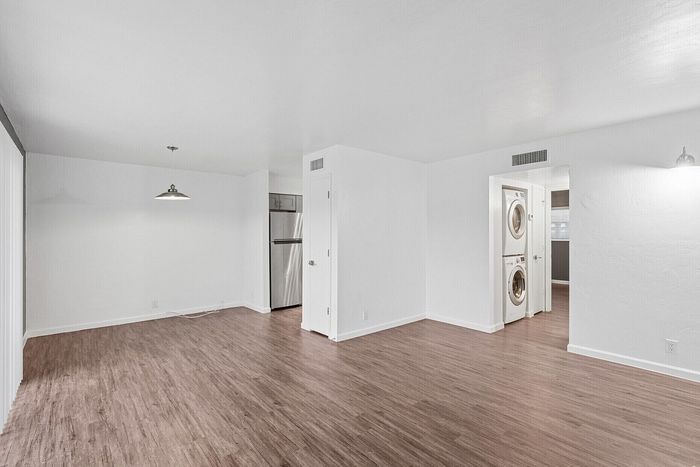 Spacious open-concept living area with elegant wood flooring, stylish lighting, and in-unit laundry for modern convenience.