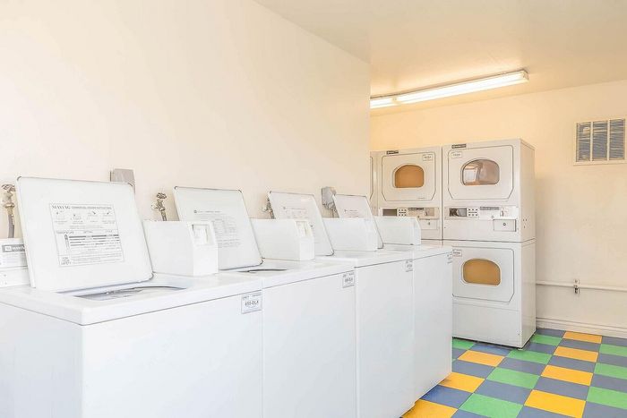 Bright and efficient laundry room with modern washers and dryers, featuring colorful checkered flooring.