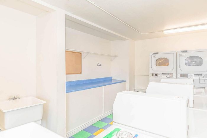 Bright and inviting laundry room featuring modern washers and dryers, ample folding space, and colorful tile flooring.