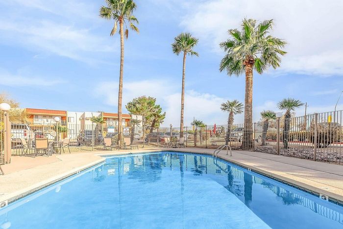 Inviting outdoor pool area surrounded by palm trees, offering a serene retreat in a sunny, resort-like setting.