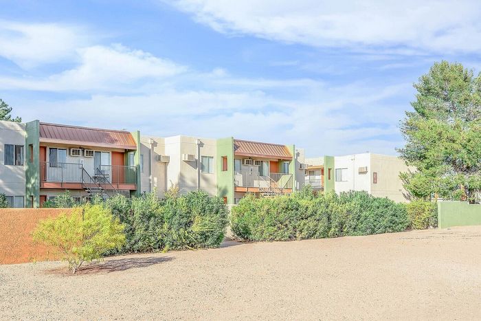 Charming apartment complex with colorful facades, surrounded by lush greenery and abundant natural light.