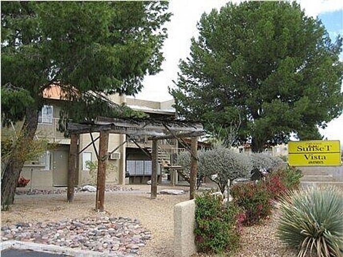 Charming apartment exterior with rustic wooden structure and lush greenery at Sunset Vista.