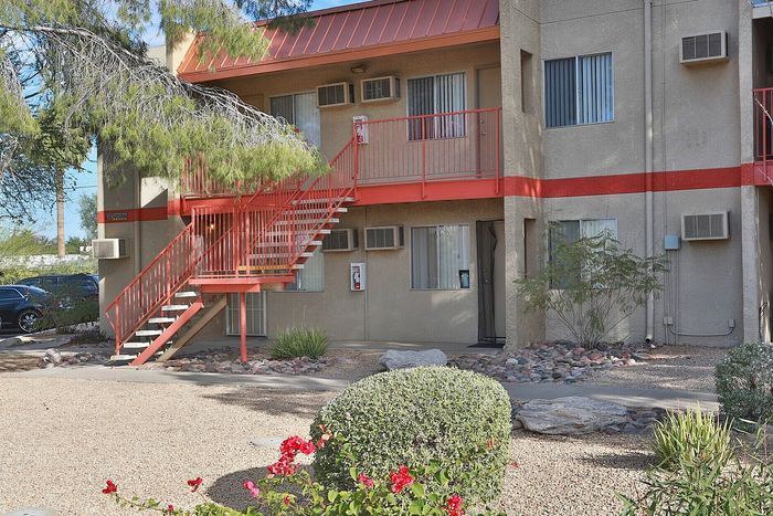 Inviting apartment building exterior with vibrant landscaping, private balconies, and convenient parking.