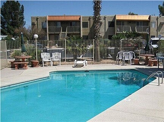 Inviting pool area with sun loungers and umbrellas in a serene apartment complex, ideal for relaxation.
