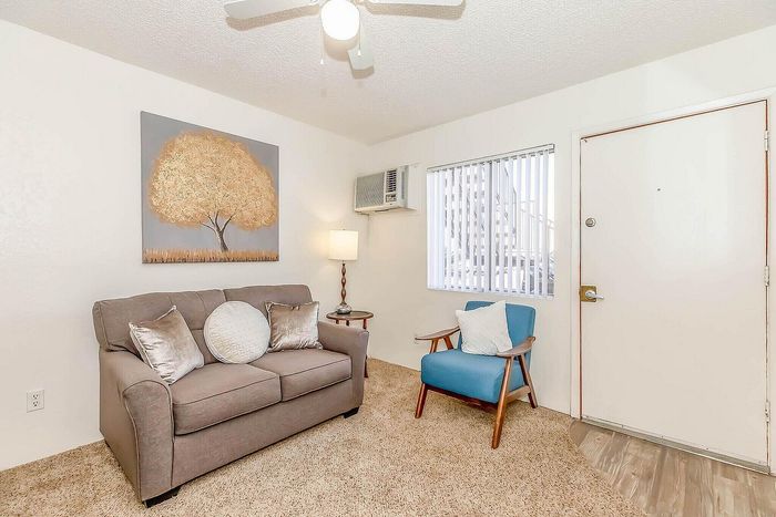 Inviting living room with cozy beige sofa, vibrant blue chair, modern artwork, and soft lighting, creating a warm and welcoming atmosphere.