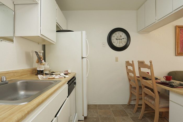 Cozy and efficient kitchen with classic white cabinets, modern appliances, and an inviting dining nook featuring stylish wooden chairs.