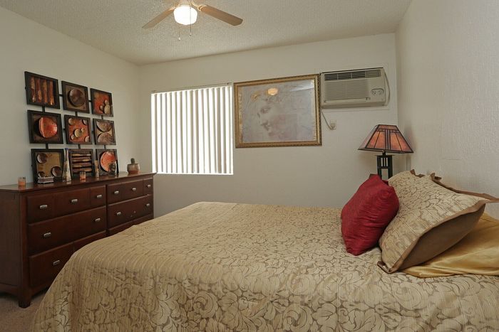 Cozy bedroom featuring a warm, elegant design with a textured bedspread, stylish wall art, and a wooden dresser under soft lighting.